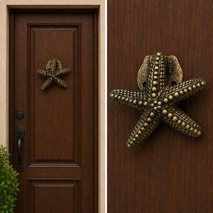 May include: A bronze-toned metal door knocker shaped like a five-pointed starfish with a textured, beaded surface. The starfish is mounted on a dark brown wooden door, featuring a weathered metallic finish with dark highlights in the crevices.