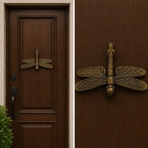 May include: A bronze-toned dragonfly door knocker mounted on a dark brown wooden door. The metal dragonfly features detailed wing textures and a segmented body, positioned horizontally as a functional piece of hardware for home entryways.