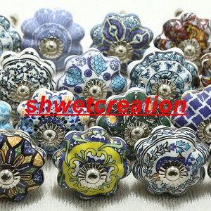 May include: Assortment of 18 ceramic drawer knobs with various colourful floral patterns. Each knob has a silver metal base.