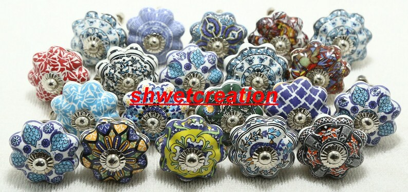 May include: Assortment of 18 ceramic drawer knobs with various colourful floral patterns. Each knob has a silver metal base.