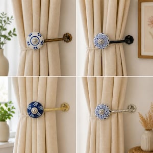 May include: Four curtain tiebacks featuring round ceramic knobs with blue and white floral patterns. Each knob is attached to a metal arm in various finishes including antique brass, black, gold, and silver, mounted to hold beige fabric curtains.