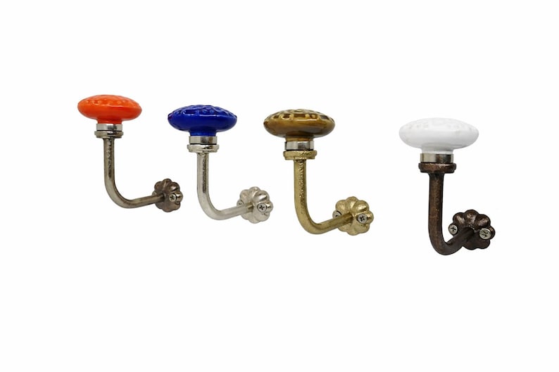May include: Four decorative wall hooks with colorful ceramic knobs. The knobs are orange, blue, gold, and white. The hooks have a curved design and are made of metal. These hooks are ideal for hanging coats, hats, or other items.