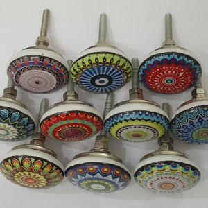 Puede incluir: Conjunto de diez pomos de armario de cer&aacute;mica coloridos con intrincados dise&ntilde;os de mandala. Cada pomo presenta un patr&oacute;n diferente con un fondo blanco y detalles plateados.
