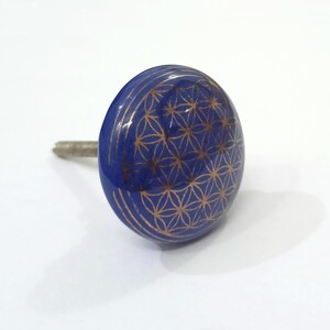 May include: A blue ceramic cabinet knob with a gold flower of life design.
