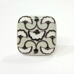 May include: Square ceramic knob with a black and white floral design on a light green background.