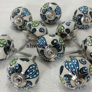May include: Ten ceramic knobs with a white background and blue, green, and yellow floral designs. Each knob has a silver base and screw.