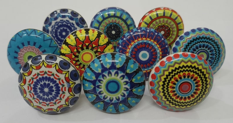 Może przedstawiać: Dziesięć kolorowych ceramicznych gałek z misternymi wzorami mandali w odcieniach niebieskiego, czerwonego, ż&oacute;łtego, zielonego i białego.