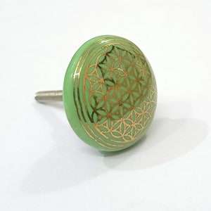 May include: Green ceramic cabinet knob with a gold flower of life design.