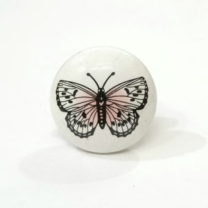 May include: White ceramic knob with a black and pink butterfly design.