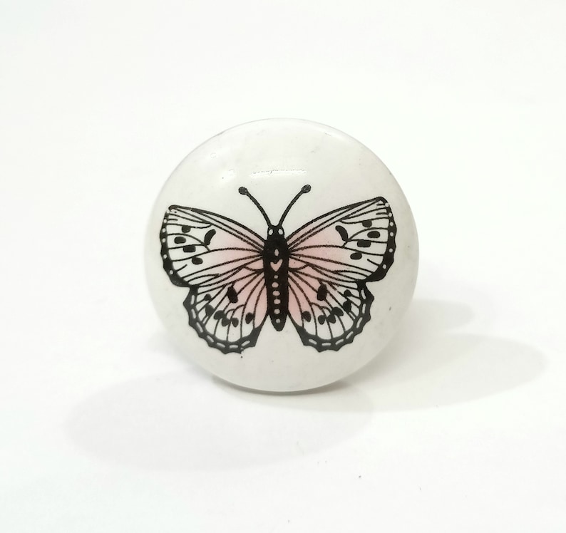 May include: White ceramic knob with a black and pink butterfly design.