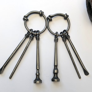 Puede incluir: Dos juegos de llaveros de metal de estilo antiguo con tres llaves cada uno. Las llaves están unidas a un anillo circular con un nudo decorativo. Las llaves tienen un acabado plateado.