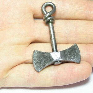 May include: A small, silver-colored, double-headed axe pendant with a twisted loop at the top.