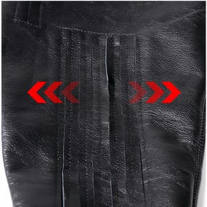 A close-up view of a black leather item with a distinctive texture, featuring a series of red arrows pointing in opposite directions.