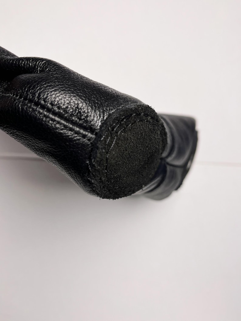 A close-up view of a black leather boot or shoe, with a black sole visible.
