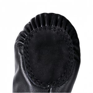 A close-up view of a black leather shoe sole with a circular, embossed design.