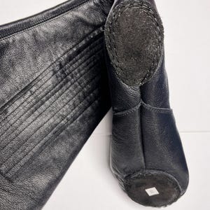 A close-up view of a black leather boot, with a label on the sole.