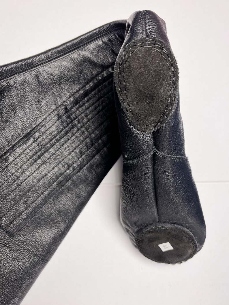 A close-up view of a black leather boot, with a label on the sole.