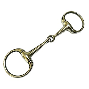 May include: A shiny, gold-coloured horse bit, featuring a ring at each end and a central bar. This equestrian equipment is designed for controlling a horse. The metal reflects light, showcasing its smooth surface and construction. The bit is made of metal.