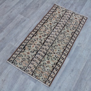 May include: A beige and brown runner rug with a geometric pattern. The rug has a fringe border and is made of wool.