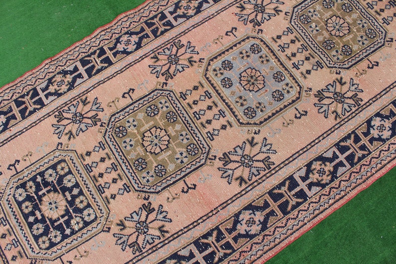 May include: A vintage pink and blue rug with a geometric pattern. The rug has a border of black and white geometric shapes.