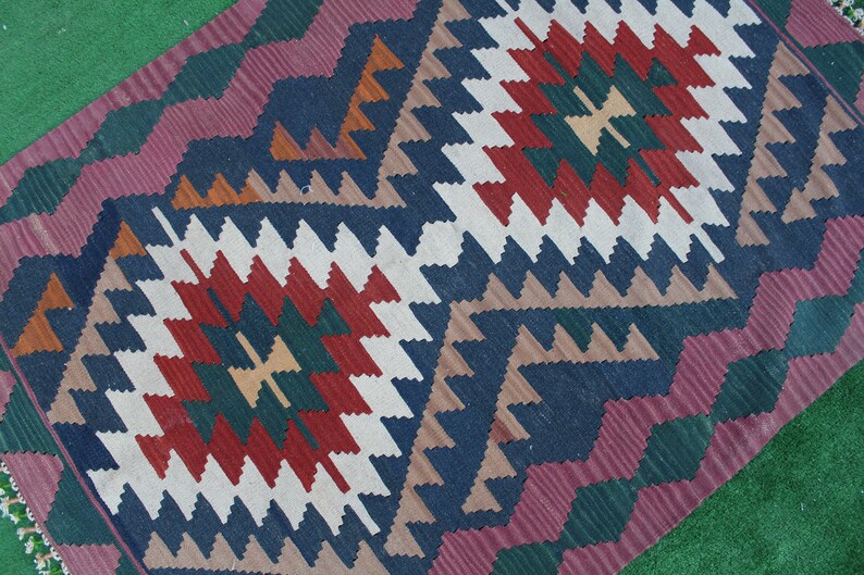 Puede incluir: Una alfombra colorida con un patr&oacute;n geom&eacute;trico en tonos de rojo, verde, azul, blanco y marr&oacute;n. La alfombra tiene un dise&ntilde;o tradicional con detalles intrincados.