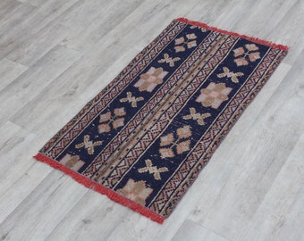 May include: A blue and red patterned rug with a fringe border. The rug has a traditional design with geometric shapes and floral motifs.