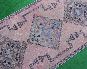 May include: A pink and blue vintage rug with a geometric pattern. The rug has a faded look and is made of wool.