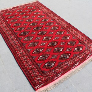 Puede incluir: Una alfombra roja con un dise&ntilde;o persa tradicional. La alfombra tiene un borde negro y una franja de color crema.