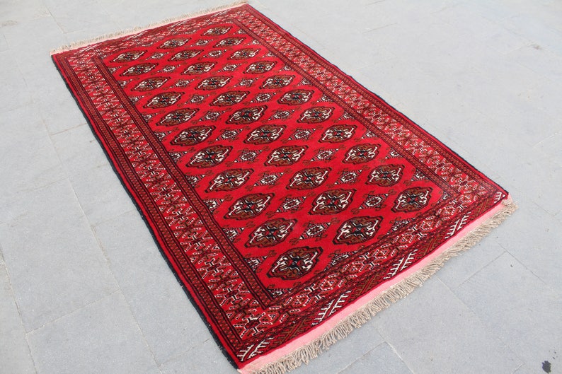 Puede incluir: Una alfombra roja con un dise&ntilde;o persa tradicional. La alfombra tiene un borde negro y una franja de color crema.