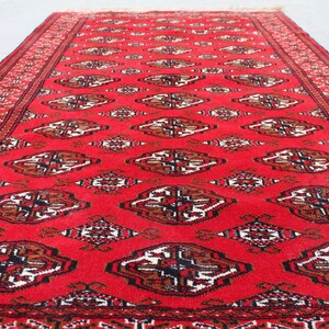 Puede incluir: Una alfombra roja con un dise&ntilde;o persa tradicional. La alfombra tiene un borde negro y patrones intrincados en tonos de marr&oacute;n y blanco.