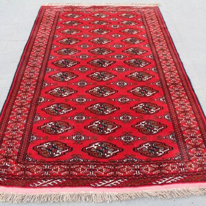 Puede incluir: Una alfombra roja con un dise&ntilde;o persa tradicional. La alfombra tiene un borde negro y blanco y una franja.
