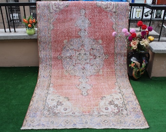 May include: A vintage pink and white rug with a floral pattern. The rug has a faded look and is made of wool.