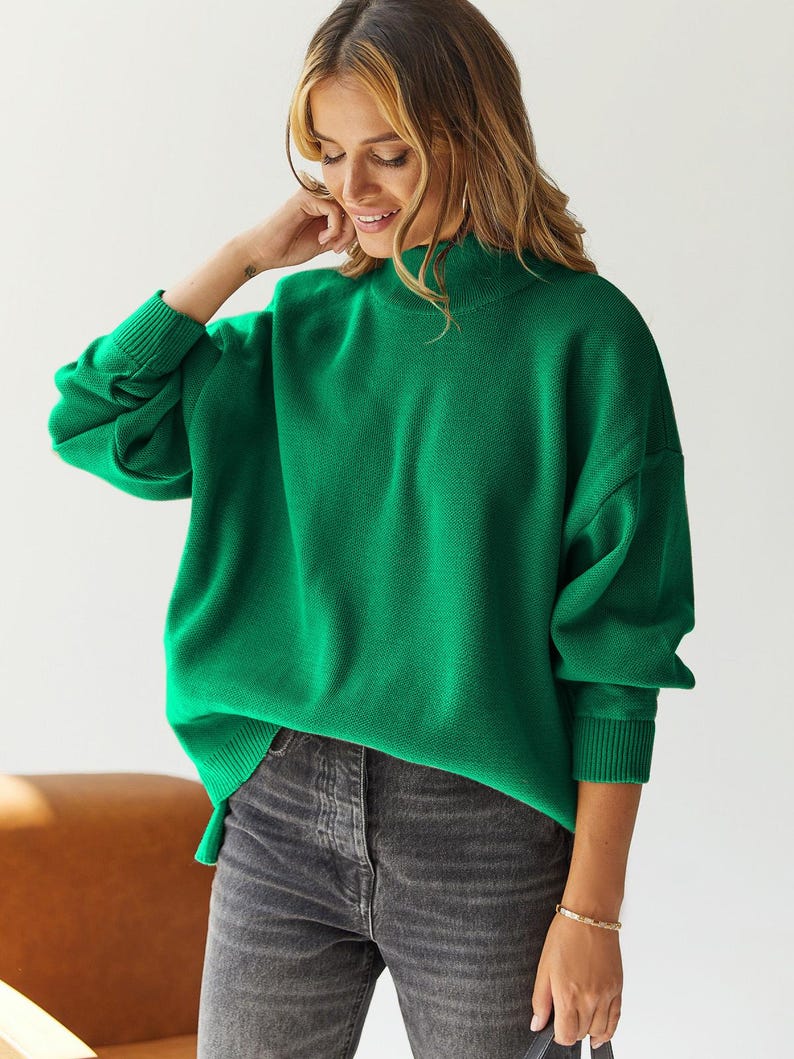 Puede incluir: Un su&eacute;ter de cuello alto verde brillante con mangas largas y un ajuste holgado.