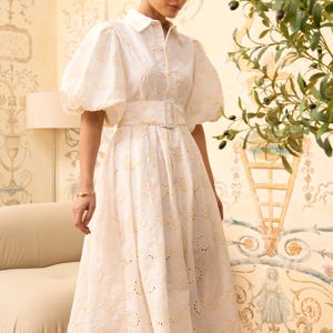 Pure white jacquard maxi shirt dress with voluminous puffed sleeves, a collared neckline, and a wide self-fabric buckled belt. Ideal for summer or bridal events.