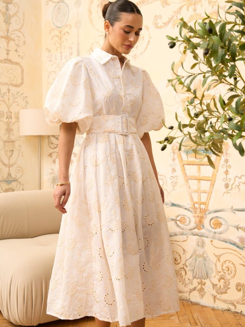Pure white jacquard maxi shirt dress with voluminous puffed sleeves, a collared neckline, and a wide self-fabric buckled belt. Ideal for summer or bridal events.
