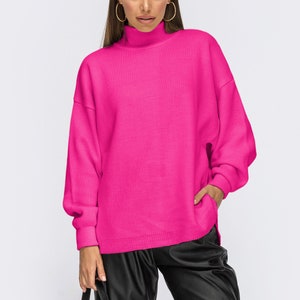 Puede incluir: Un jersey de cuello alto de color rosa brillante con mangas largas y un corte holgado.