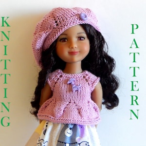 May include: A pink knitted doll outfit with a matching beret. The outfit features a sleeveless top with a delicate lace pattern and a small flower embellishment. The doll has long, dark curly hair and brown eyes.