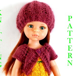 Puede incluir: Una muñeca con un gorro, un cárdigan y un vestido de punto burdeos. La muñeca tiene el pelo largo y rojo y los ojos azules. El texto "KNITTING" y "PATTERN" es visible a ambos lados de la muñeca.