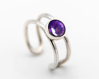 May include: A silver ear cuff with a purple amethyst gemstone. The cuff has a double band design.