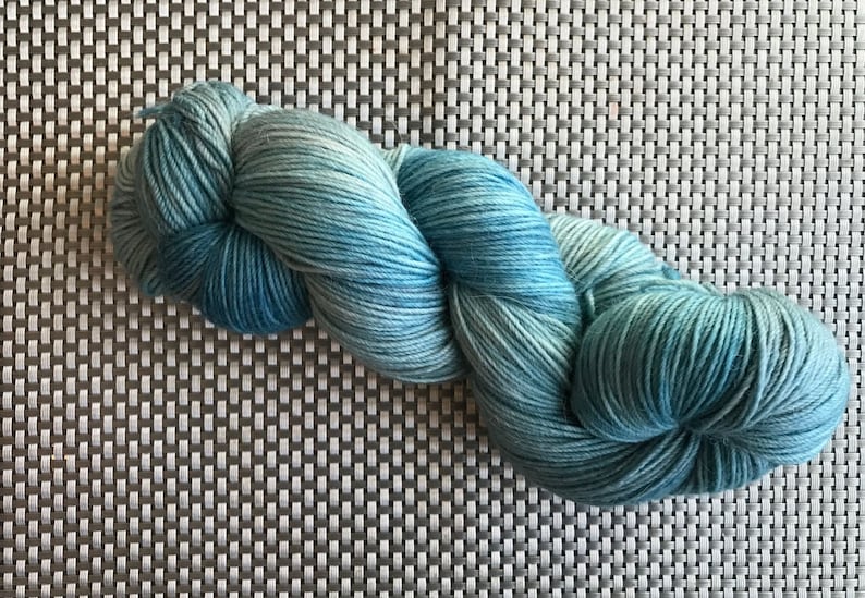 in shades of pale aqua blue with pale grey 115 g size fingering Merino and nylon Aeolus bottom yarn hand dyed