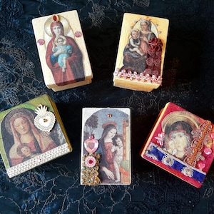 May include: Five small, rectangular boxes with religious imagery. The boxes feature images of the Virgin Mary and Jesus, with decorative embellishments like beads and lace. The color palette includes reds, blues, and golds.