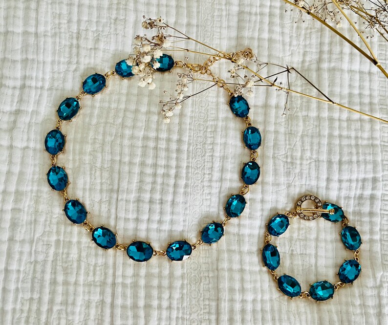 K&ouml;nnte beinhalten: Ein Set aus zwei t&uuml;rkisblauen Kristallketten mit ovalen Steinen. Die gr&ouml;&szlig;ere Kette ist ein Choker und die kleinere Kette ist ein Armband.