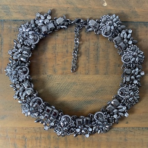 May include: A black statement necklace with a large, ornate design featuring black and clear rhinestones.