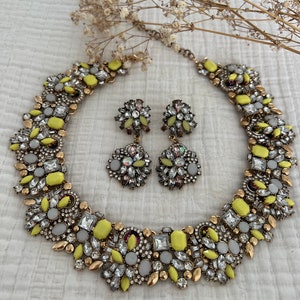 May include: A yellow and gold statement necklace and matching earrings with a cluster of rhinestones and yellow stones.