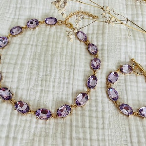 K&ouml;nnte beinhalten: Ein Set aus goldfarbenem Schmuck mit einer Halskette und einem Armband mit ovalen, lavendelfarbenen Strasssteinen.