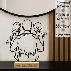 Könnte beinhalten: Ein schwarzes Holzschild mit Linienkunst, das einen Elternteil mit zwei Kindern zeigt, mit den Namen "Marie" und "Ben", darunter das Wort "Papa". Das Schild steht auf einem Holzsockel mit dem Text "Wir haben dich lieb." Zusätzlicher Text rechts.