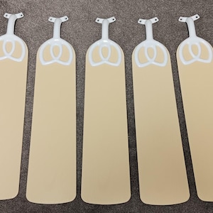 May include: A set of five ceiling fan blades, each featuring a light beige finish and a white decorative accent near the mounting bracket. The blades are long and rectangular with rounded ends, designed for attachment to a central fan motor.