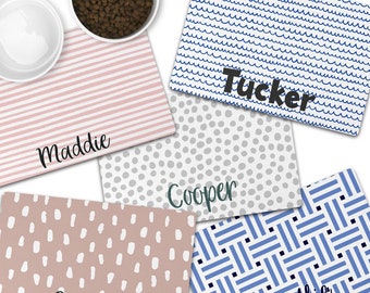 Puede incluir: Cinco manteles individuales rectangulares para mascotas con varios patrones y nombres personalizados. Los patrones incluyen rayas rosas, ondas azules, puntos grises, rosa con rayas blancas y un diseño tejido azul. Nombres: Maddie, Tucker, Cooper, Kallie.