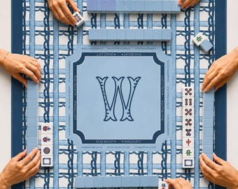 May include: A square mahjong game mat with a blue and white woven pattern, featuring a central light blue square with a large letter W and game instructions. The mat includes various mahjong tiles with symbols and characters arranged around the edges.