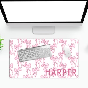 May include: White desk mat with a pink bow pattern and the name "HARPER" in pink letters. A silver keyboard and a white mouse are on the mat.